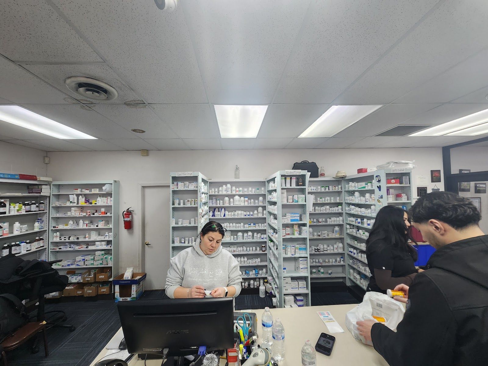 Inside Melvindale Pharmacy: the pharmacy counter with medicine shelves behind it