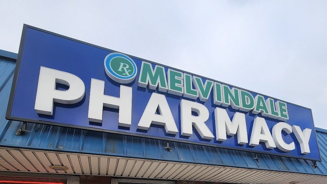 Close-up of the blue MELVINDALE PHARMACY sign over the door